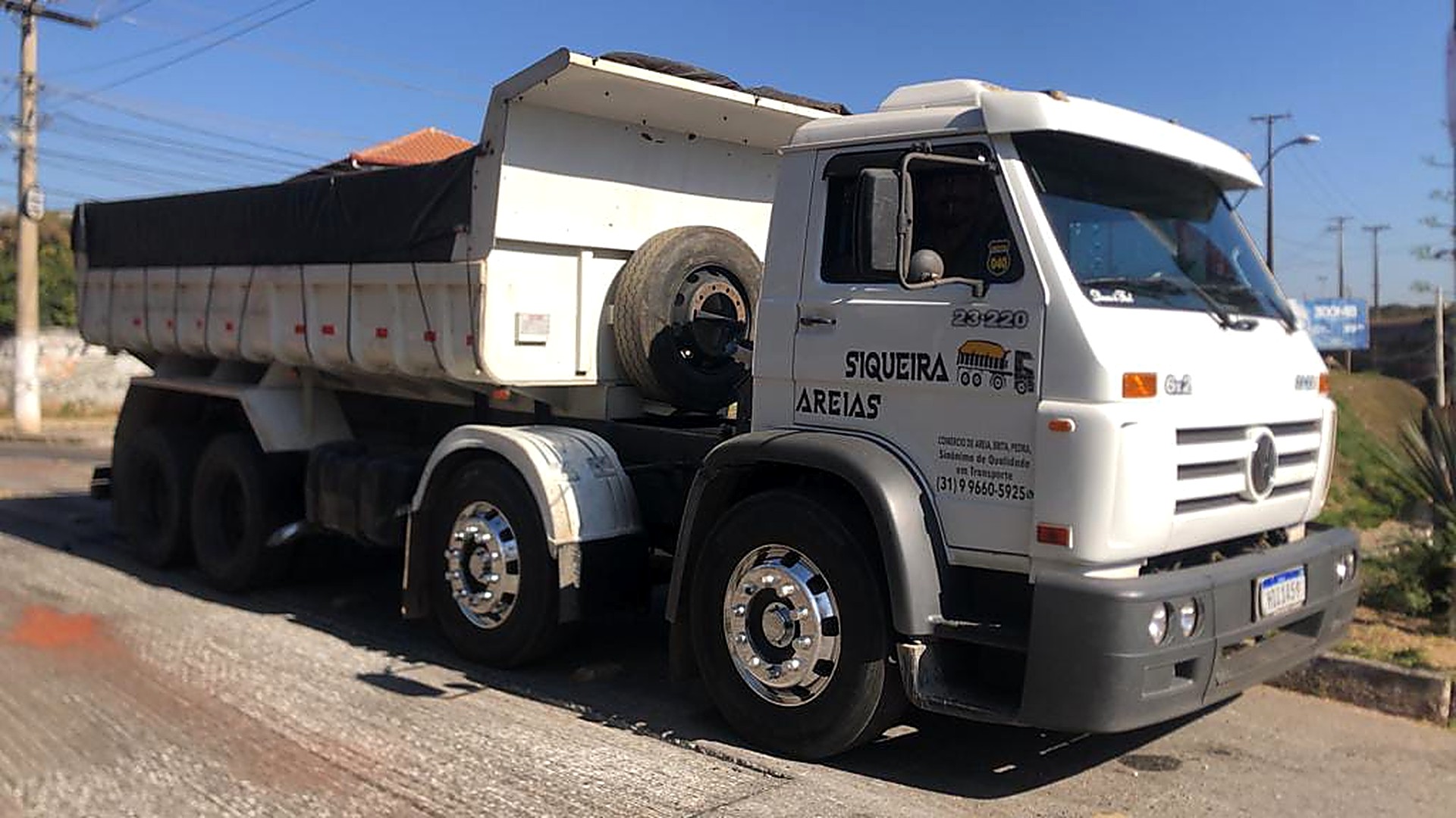 Caminhão basculante branco da Siqueira Areias com caçamba carregada em via de Belo Horizonte